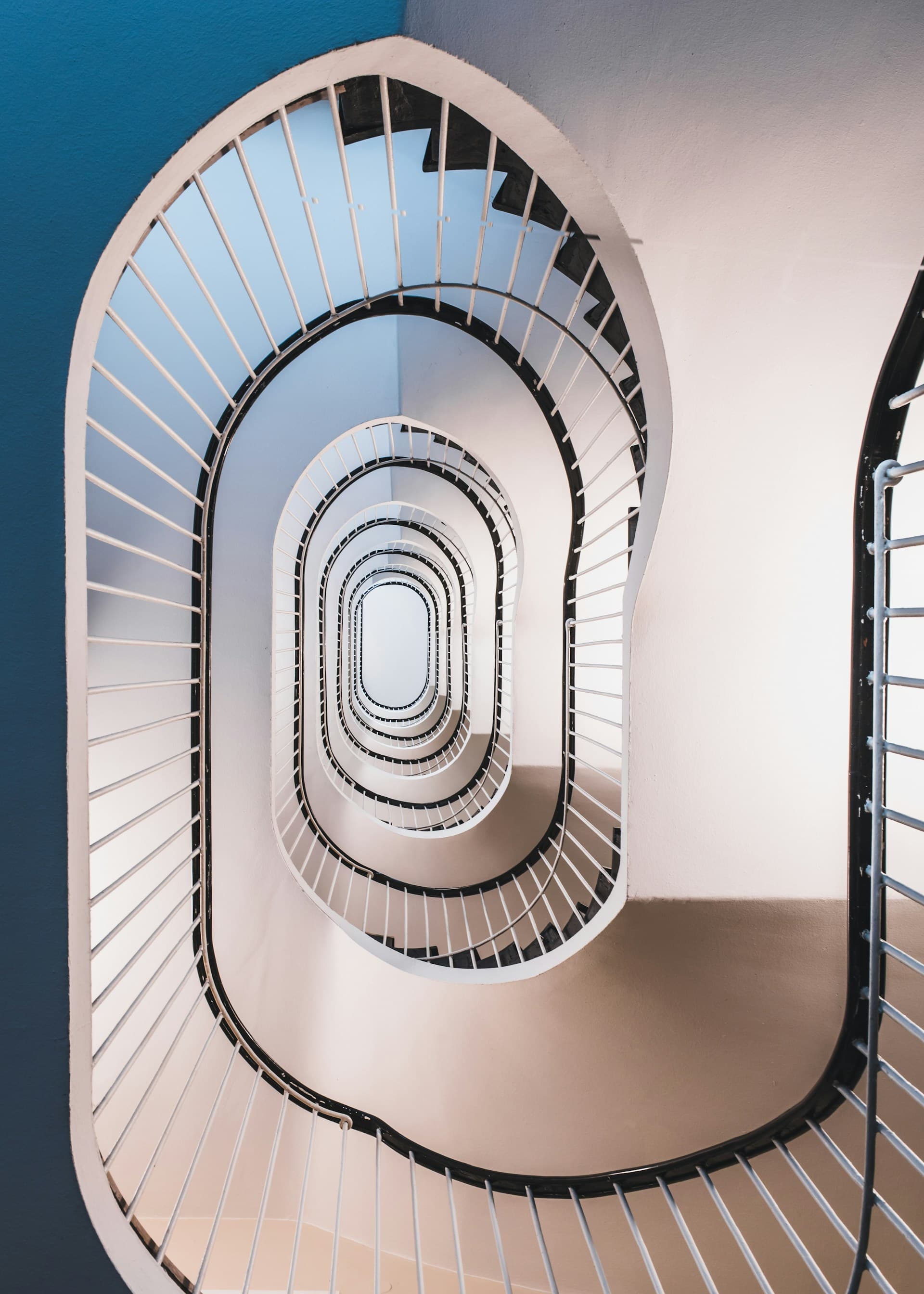 Escalera en espiral vista desde abajo, con barandas blancas que se repiten hacia el centro